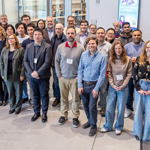 About 40 people stand outside of a classroom in an academic building